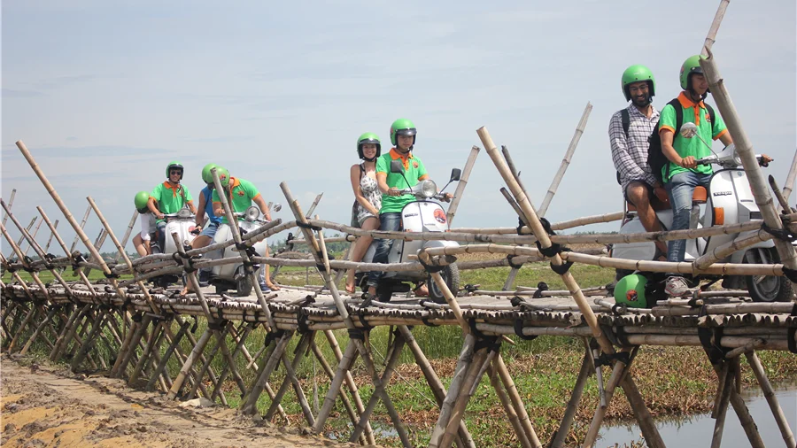 Vespa riders on a bamboo bridge outside Hoi An