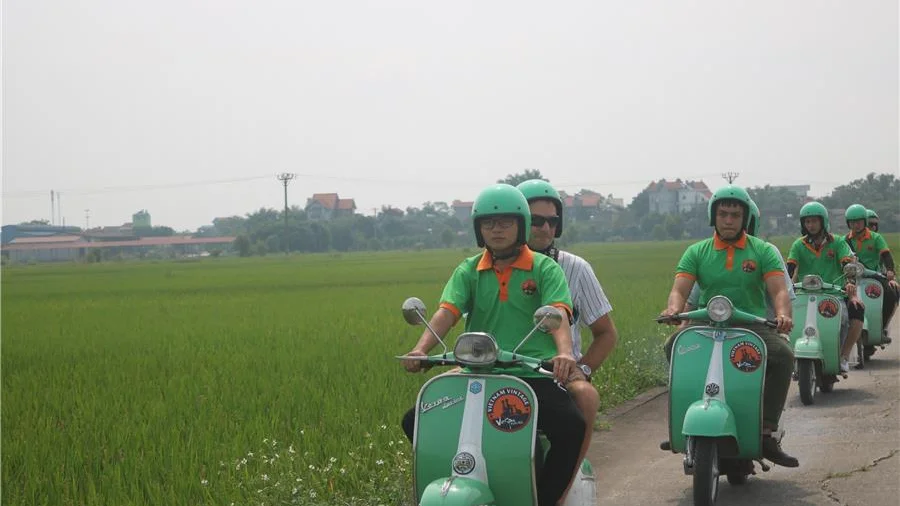 Travellers on vintage Vespas in the green countryside near Hoi An