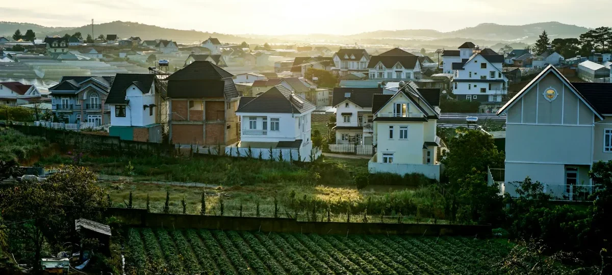 Colourful hillside villas and guesthouses above vegetable gardens in Dalat glowing in late-afternoon sun