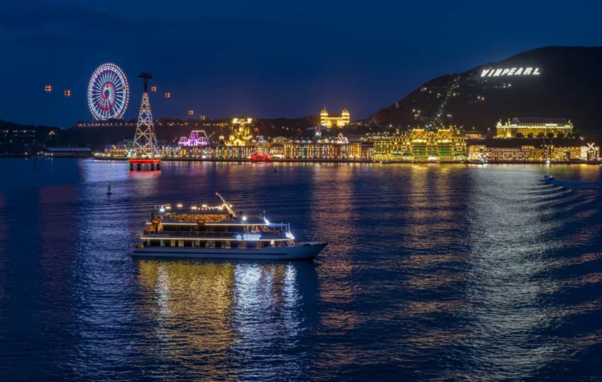 Emperor Cruises Legend lit up at night in Nha Trang Bay with the island lights behind