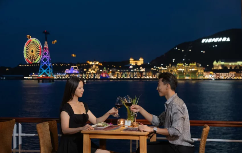 Couple dining on deck at night facing the lights of Nha Trang Bay on Emperor Cruises Legend