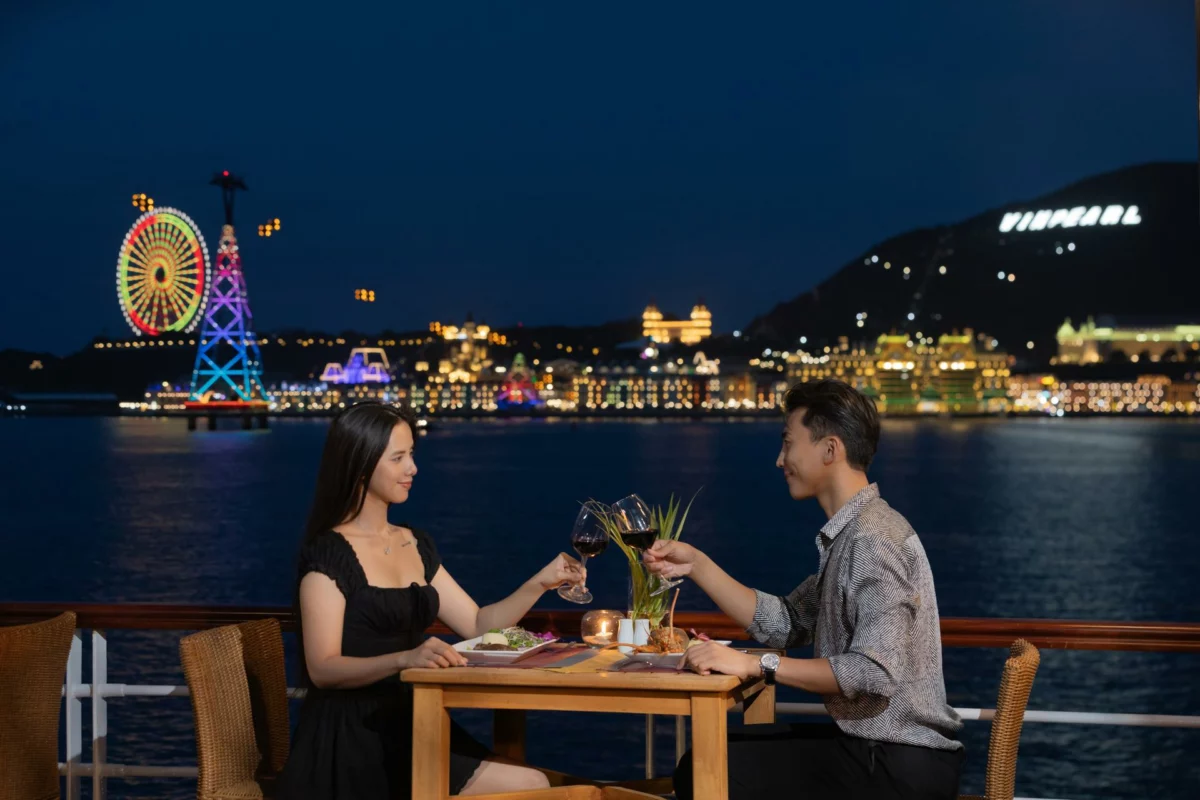Couple dining on deck at night facing the lights of Nha Trang Bay on Emperor Cruises Legend