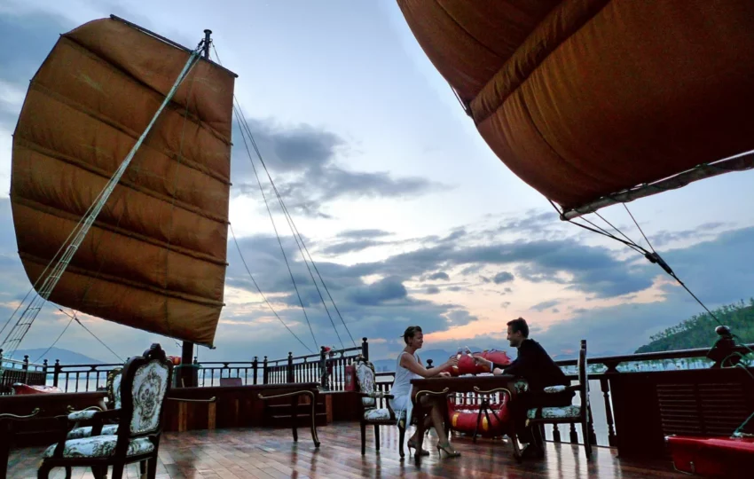 Dinner tables set on deck under the sails of Emperor Cruises Origin at dusk