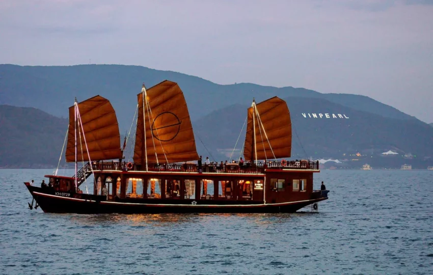 Emperor Cruises Origin, a traditional wooden junk with three orange sails, in Nha Trang Bay