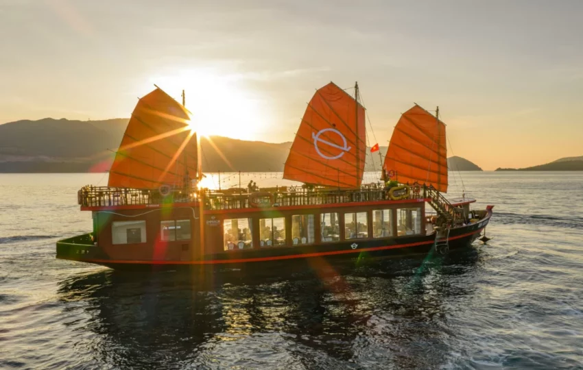 Emperor Cruises Origin junk with orange sails sailing Nha Trang Bay at sunset