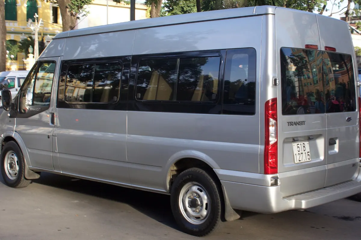 Silver Ford Transit 16-seat passenger van with a Vietnamese number plate