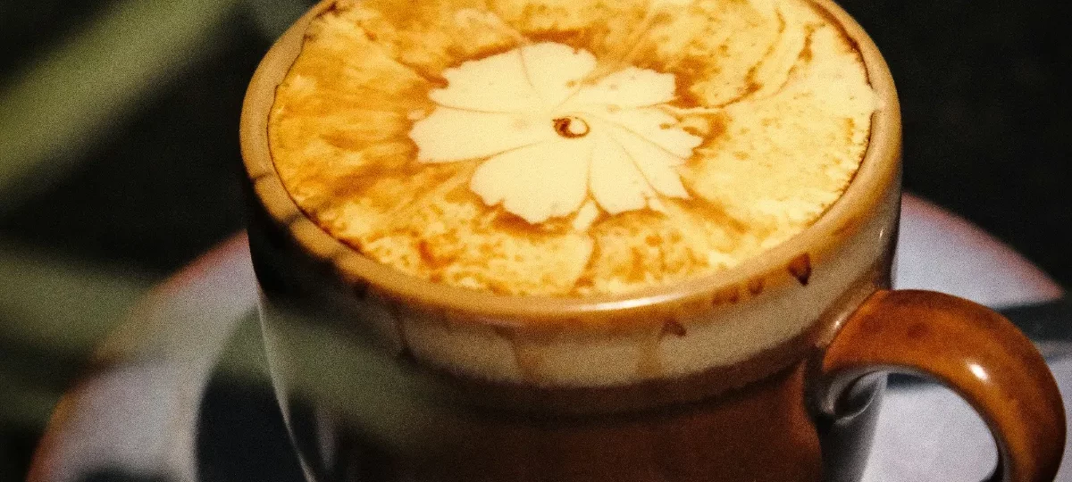 Cup of Hanoi egg coffee (cà phê trứng) with a thick golden egg foam topped with a flower pattern