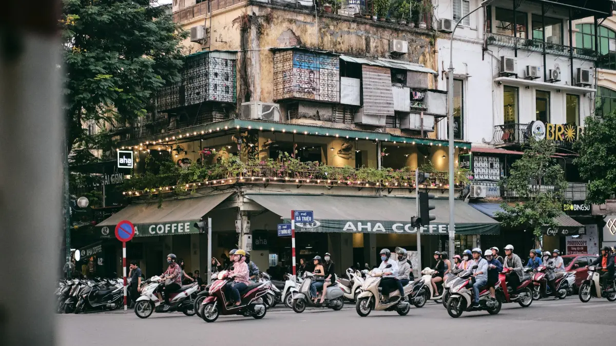 Hanoi Egg Coffee – Old Quarter Café Corner Hanoi Old Quarter street corner with cafés on the ground floor and motorbikes passing