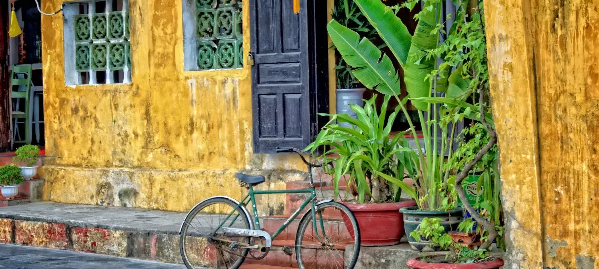 Bicycle parked outside a yellow old house with green shutters in Hoi An Ancient Town, the easiest way to get around