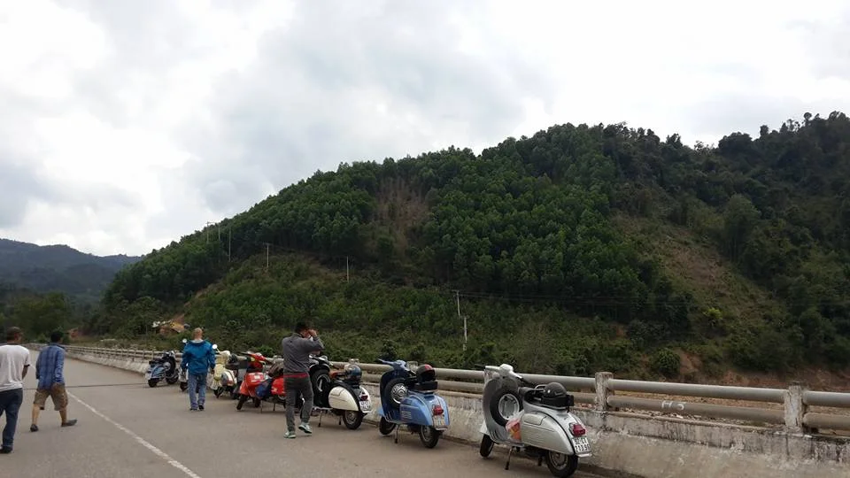 Vespas parked at a roadside stop below green mountains between Da Nang and Hue