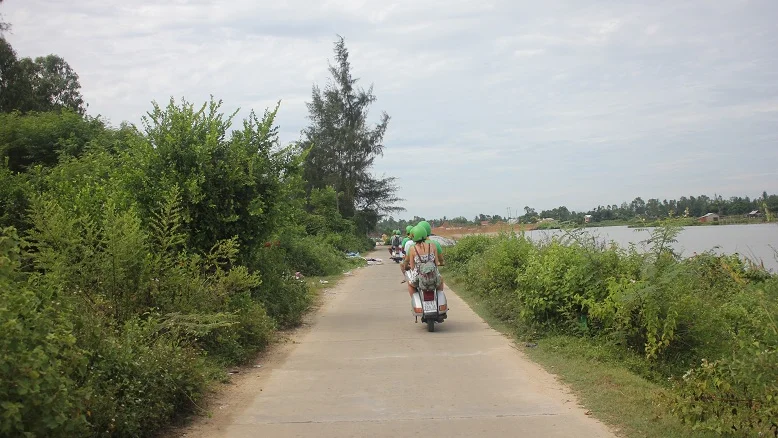 Vespas on a quiet tree-lined village lane near Hoi An