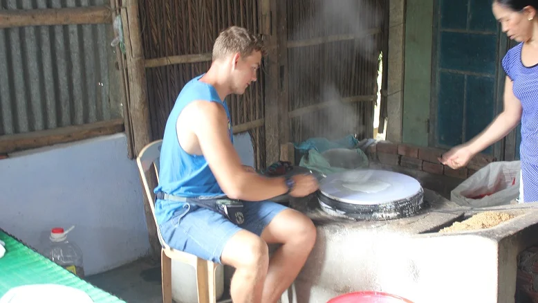 Traveller trying to make rice paper over a steamer in a village near Hoi An