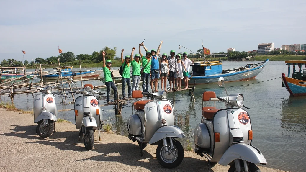 Vintage Vespas parked by the river with fishing boats
