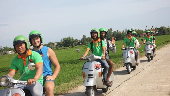 Guest riding pillion behind a Vespa driver through the countryside near Hoi An