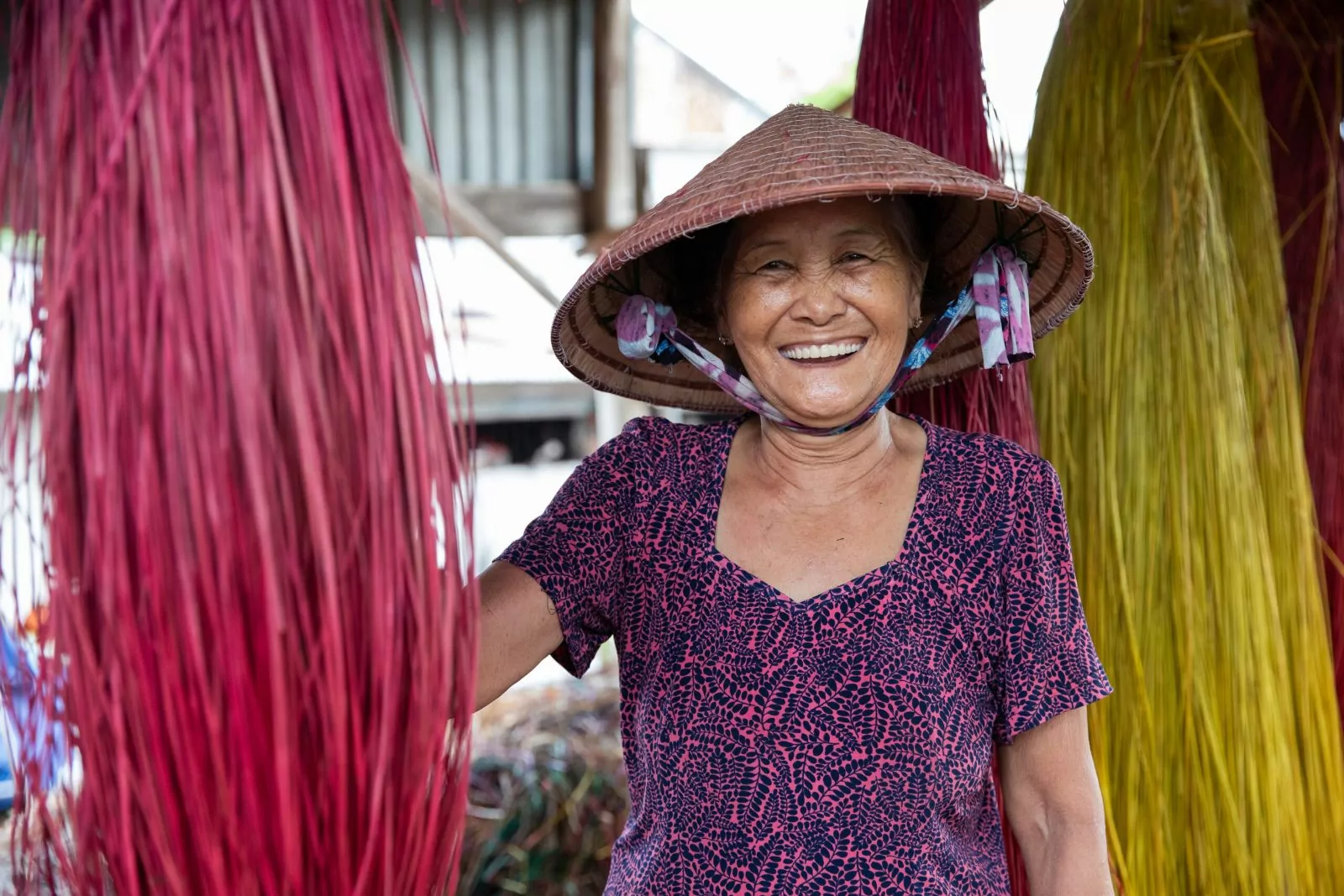 Smiling local artisan in a traditional conical hat in a Mekong village