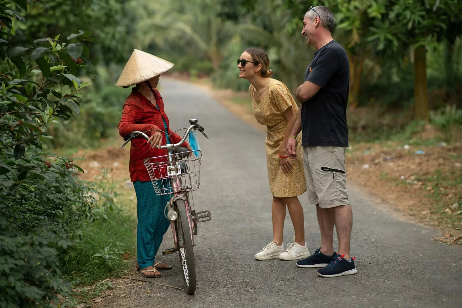 Guests walking through a Mekong village with a local woman and her bicycle