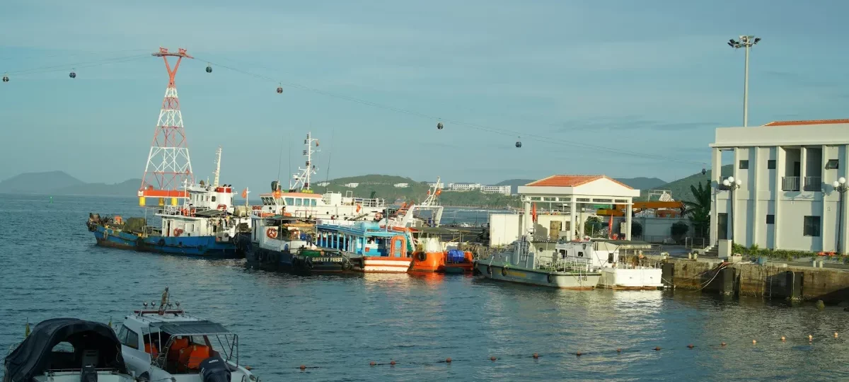 Island tour boats moored at a Nha Trang harbour with the sea cable car to Hon Tre Island overhead