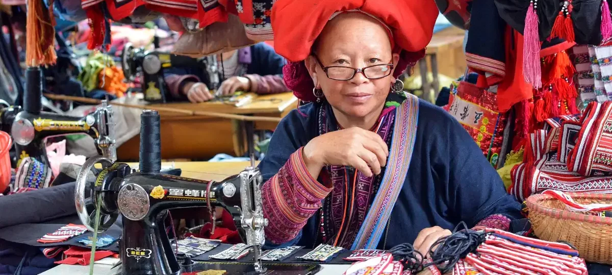 Red Dao woman in a red headscarf doing embroidery, Sapa