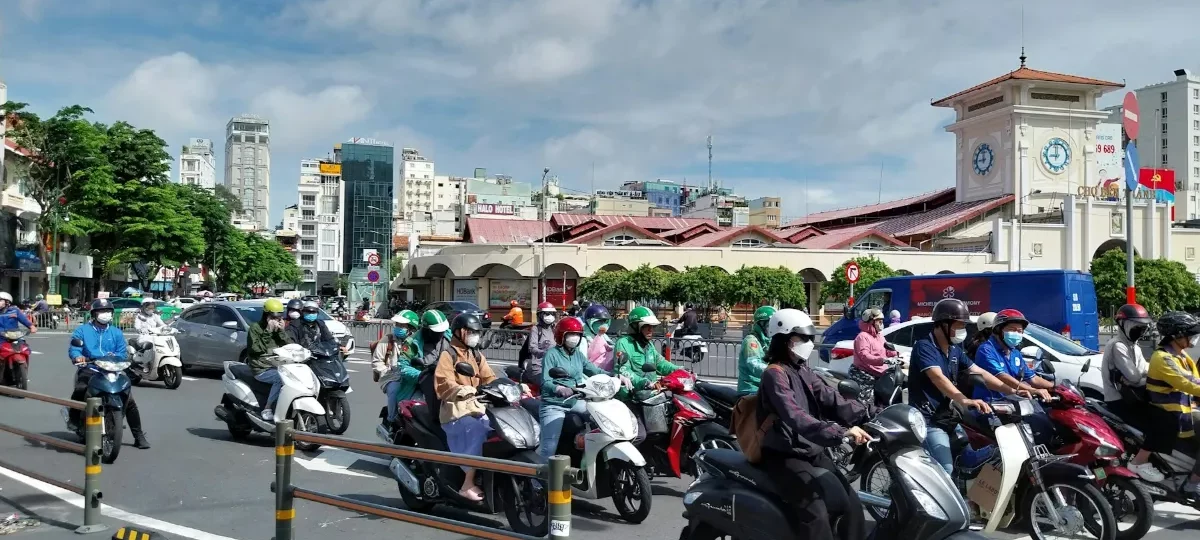 Scooters and cars circling the Ben Thanh Market roundabout in central Saigon on a sunny day