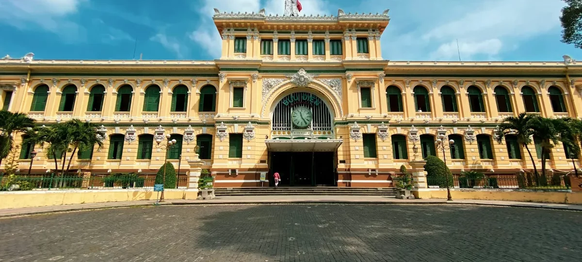 Yellow French colonial facade of the Saigon Central Post Office under a blue sky in Ho Chi Minh City