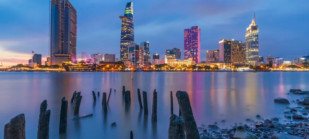 Saigon skyline at dusk seen across the Saigon River, with Bitexco Financial Tower lit up
