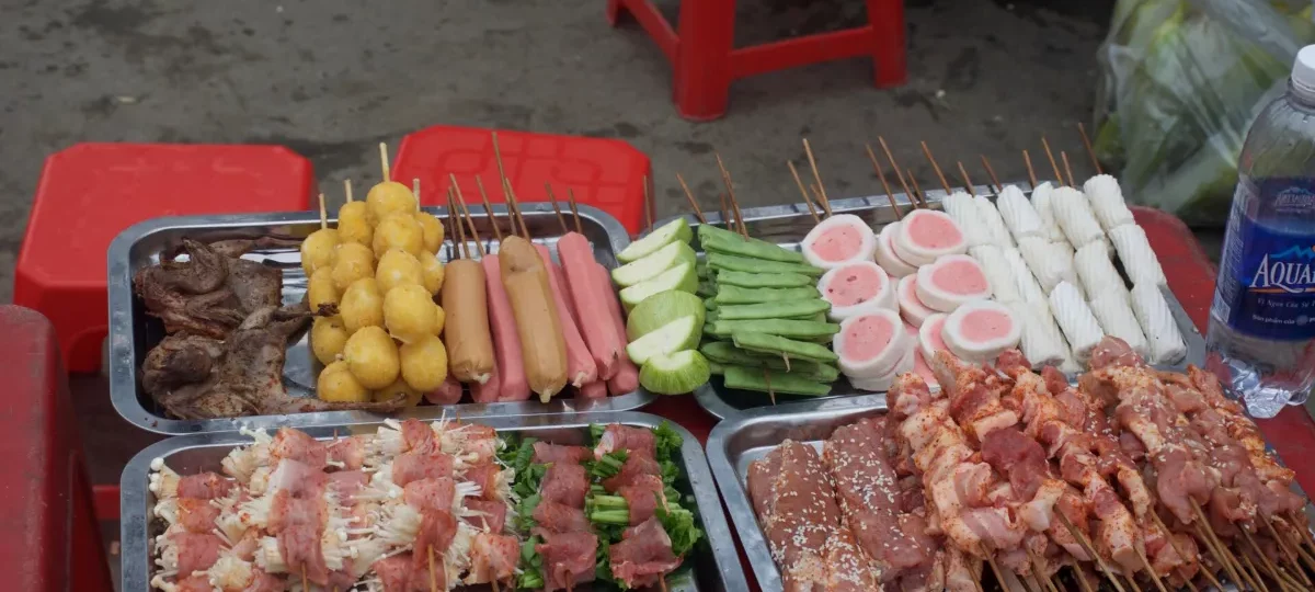 Tray of skewers, sausages and fish balls ready for the charcoal grill at a Sapa street food stall