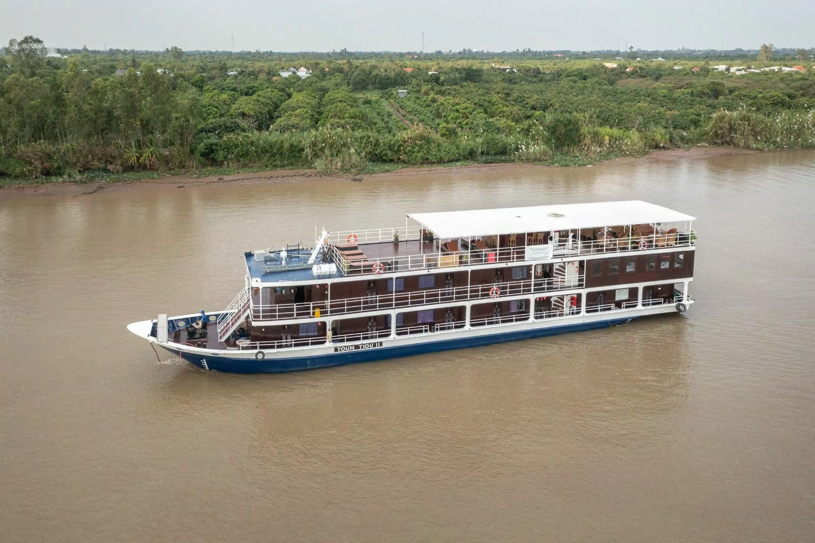 Toum Tiou II sailing past green riverbanks