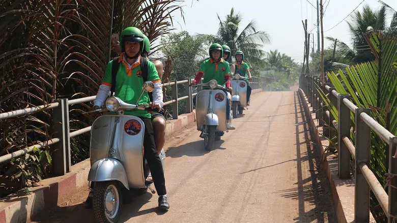Vespa crossing a village bridge