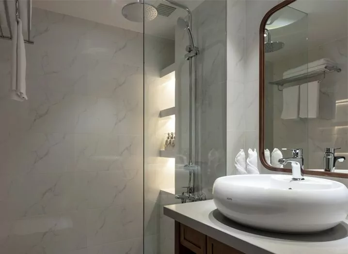 Deluxe cabin bathroom with vessel basin and walk-in glass shower on the Victoria Mekong cruise