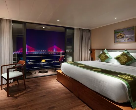 Deluxe cabin at night with city lights and a bridge seen through the balcony windows on the Victoria Mekong