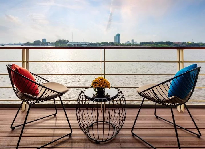 Private balcony with two chairs overlooking the Mekong River from a Victoria Mekong Deluxe cabin