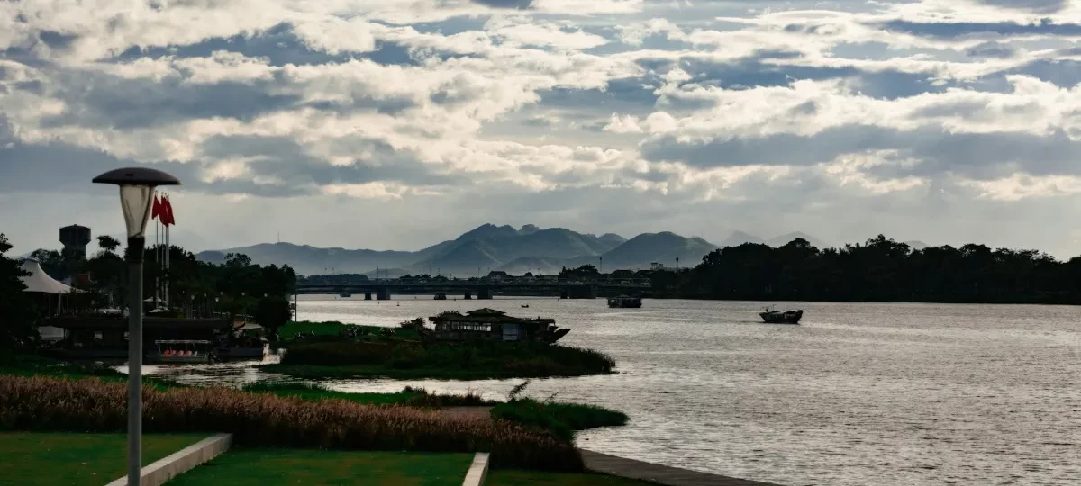 Perfume River in Hue with riverside gardens, boats and mountains, the area where many Hue hotels are located
