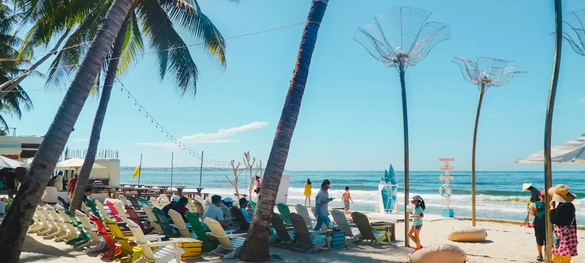 Palm trees and colourful sun loungers on a beachfront in Ham Tien, the main Mui Ne resort strip
